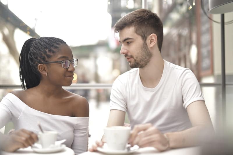 un homme et une fille sont assis à une table, boire du café et parler