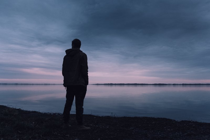 un homme se tient au bord de la rivière et pense