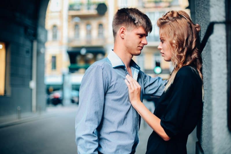un homme se tient à côté d'une femme appuyée contre un mur