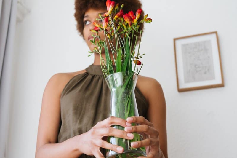 une femme avec des fleurs dans sa main se dresse