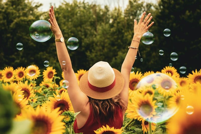 une femme avec un chapeau sur la tête dans un champ de tournesols