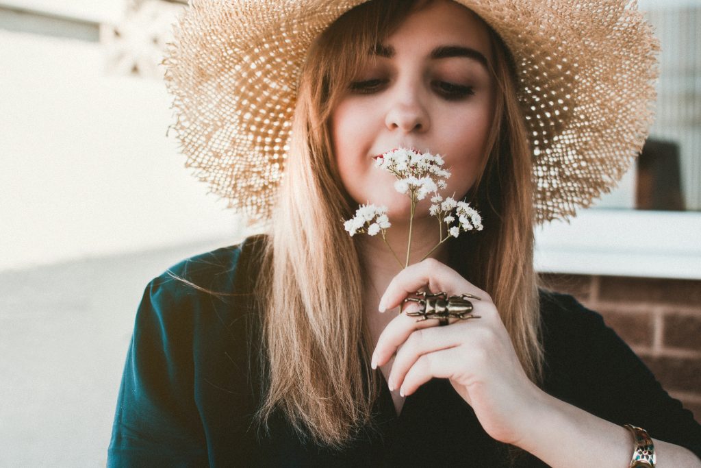 une femme avec un chapeau à la main tient une fleur