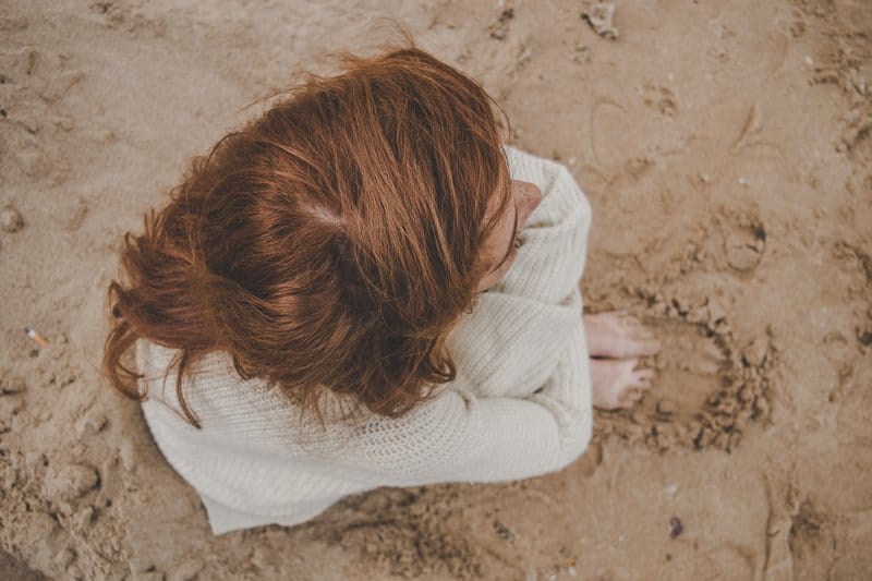 une femme rassemblée est assise sur la plage