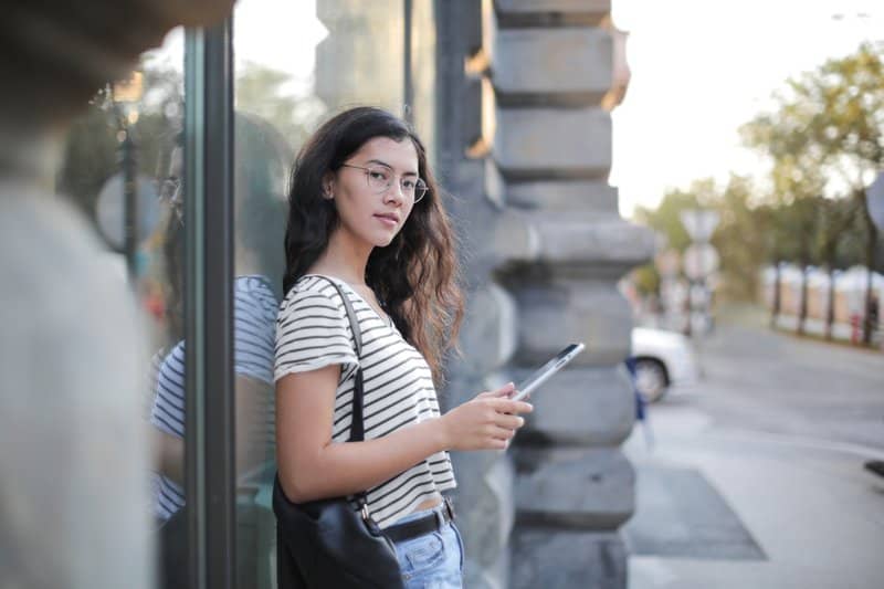 une femme se tient contre un mur et un bouton sur le téléphone