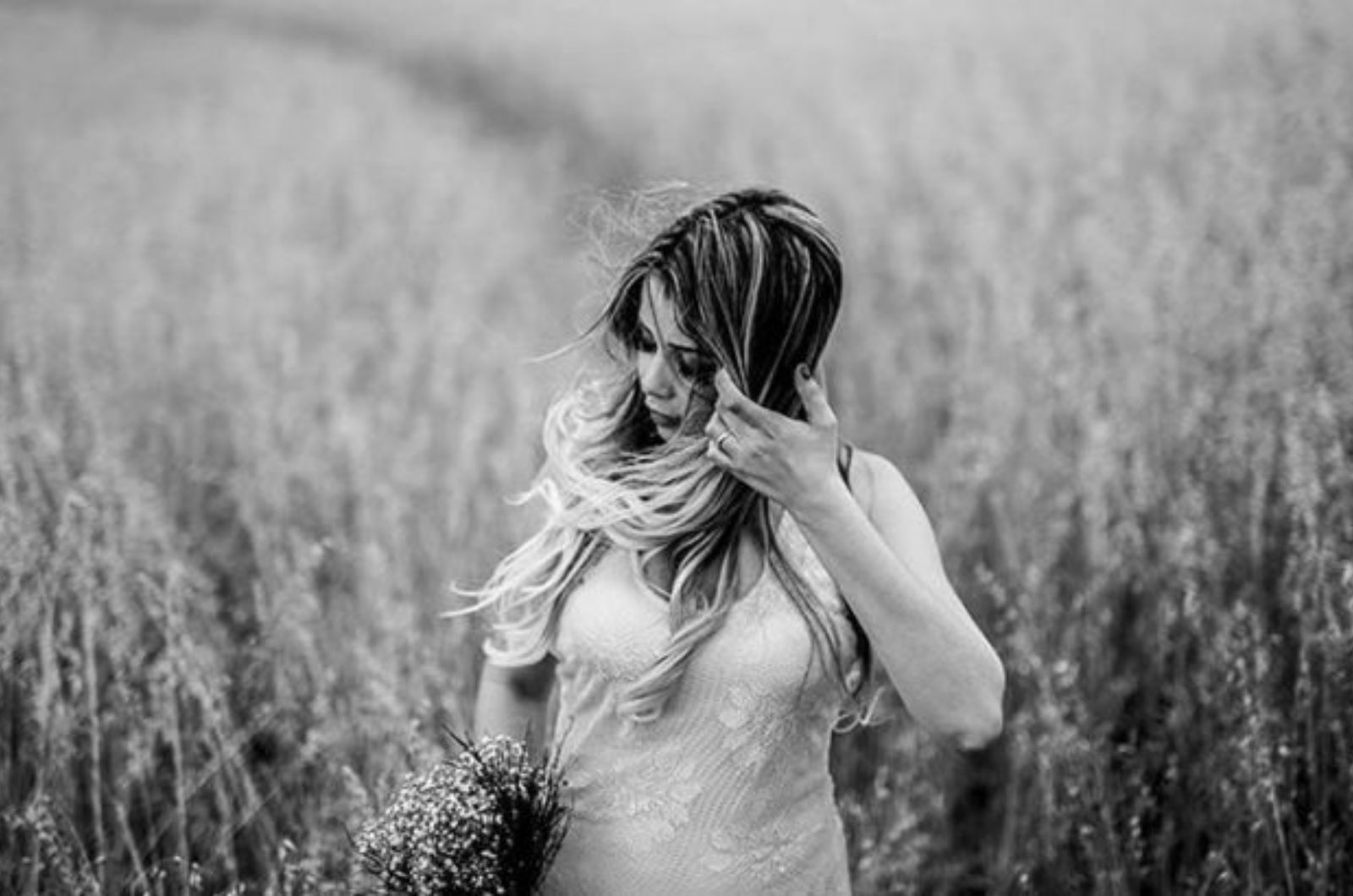 une femme avec un bouquet de fleurs se tient dans un champ