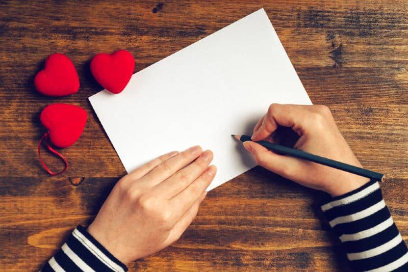 mains d'une femme écrivant une lettre d'amour
