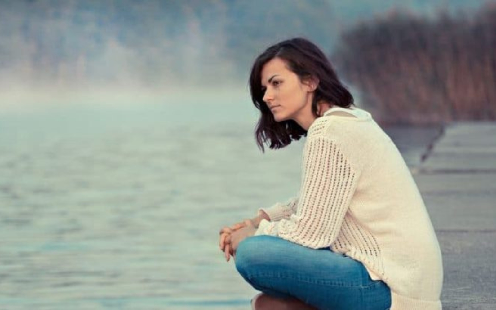 femme assise seule au bord du lac