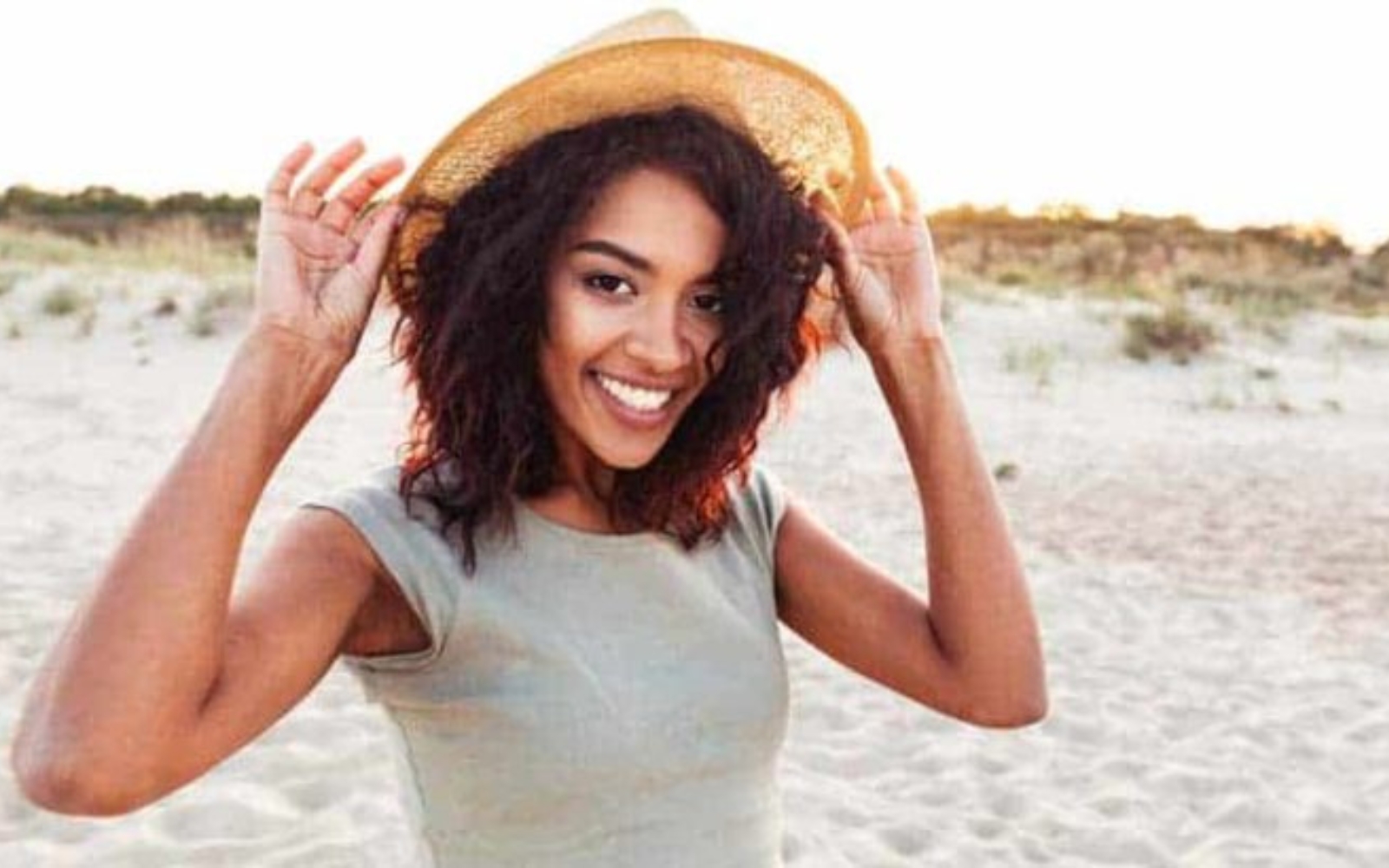 une femme debout sur la plage avec un chapeau sur la tete