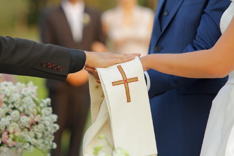 Prêtre donnant la bénédiction de sa main à un couple qui se marie