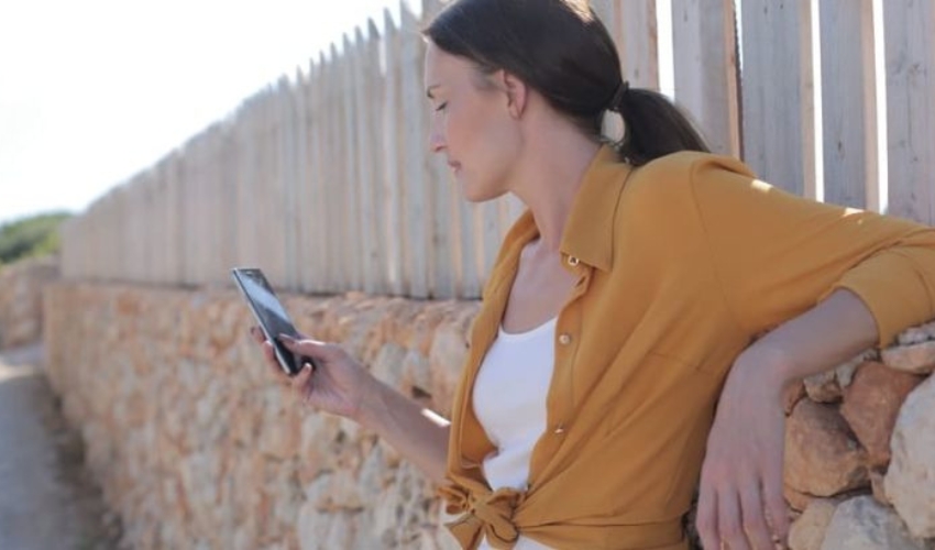 une femme aux cheveux noirs se tient avec un telephone a la main