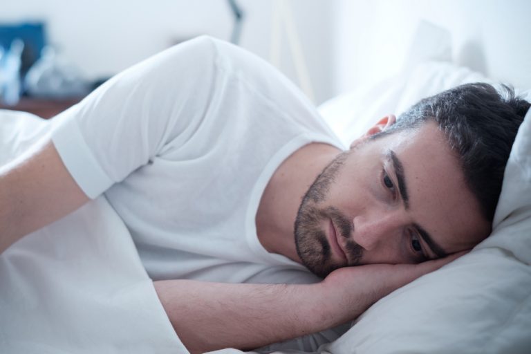 un homme triste est couché dans son lit