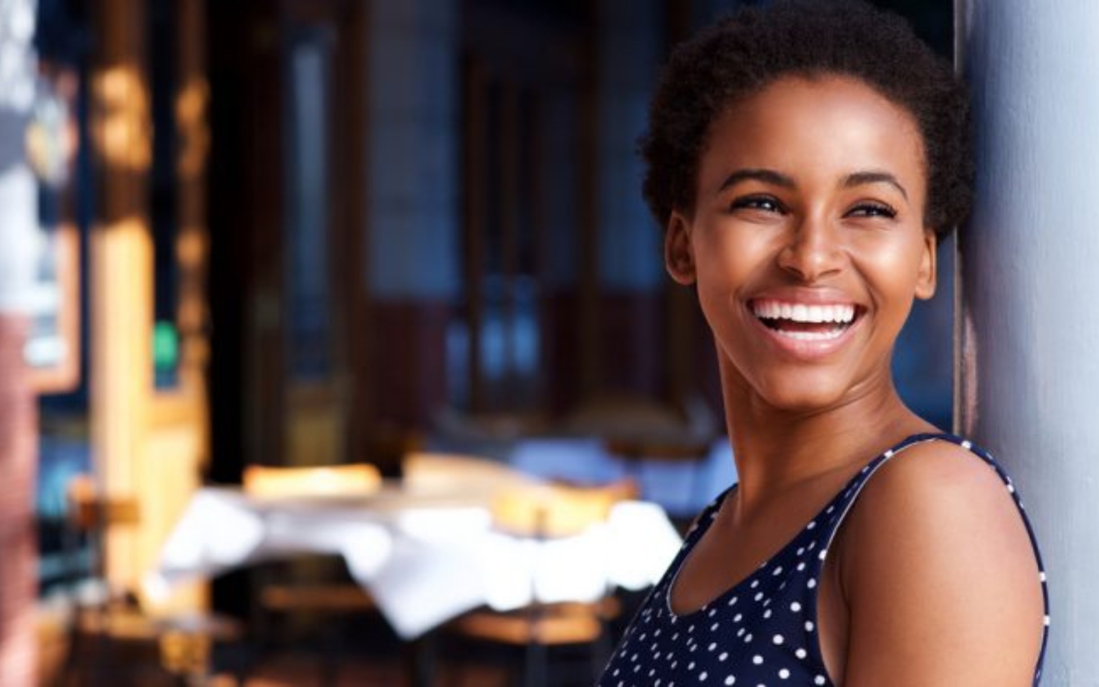 une femme aux cheveux courts noirs rit