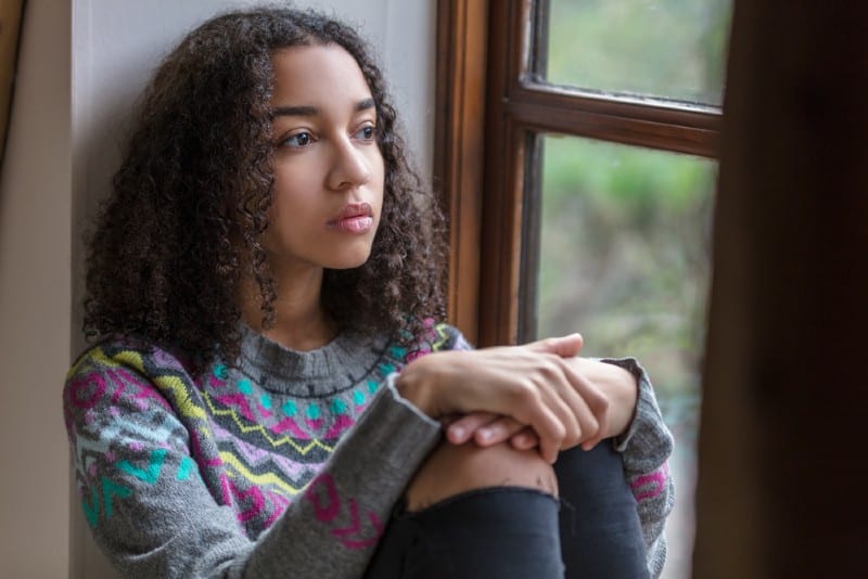 adolescent femme jeune femme triste déprimée ou réfléchie à la recherche d'une fenêtre