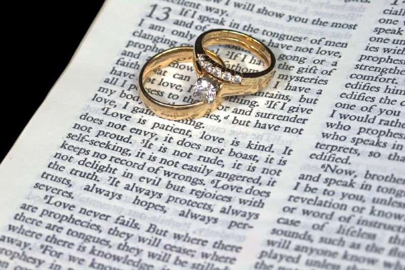  anneaux de mariage sur les pages de la Bible avec passage sur l'amour