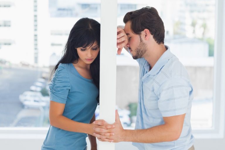 couple triste debout à différents côtés d'une porte