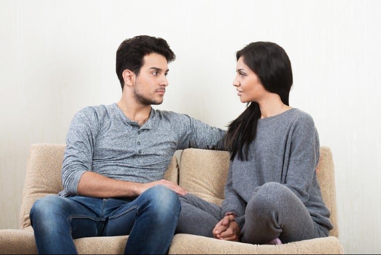 couple parlant ensemble assis sur un canapé