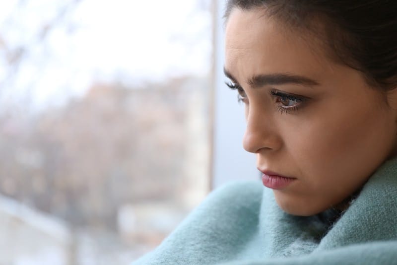 Déprimé jeune femme près de la fenêtre à la maison