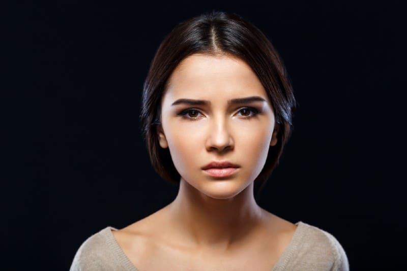 Gros plan de la pauvre jeune femme déprimée triste implorant de l'aide et va pleurer en position debout isoler sur fond noir