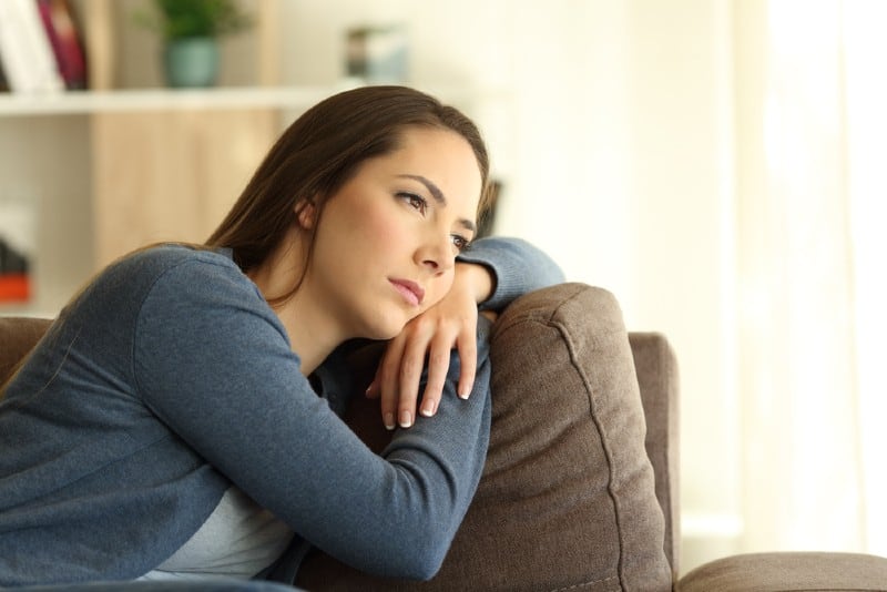 Jeune femme allongée sur le canapé et penser à quelque chose à la maison
