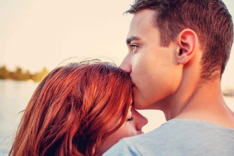 Beau jeune homme embrassant sa petite amie près de la rivière
