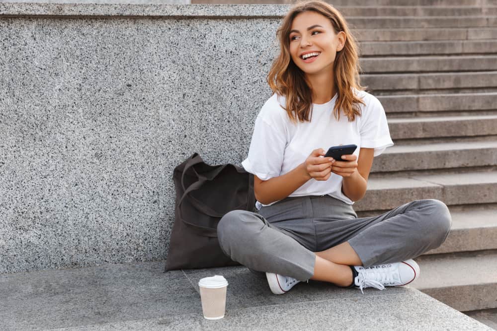 la femme est assise avec le téléphone à la main et rit