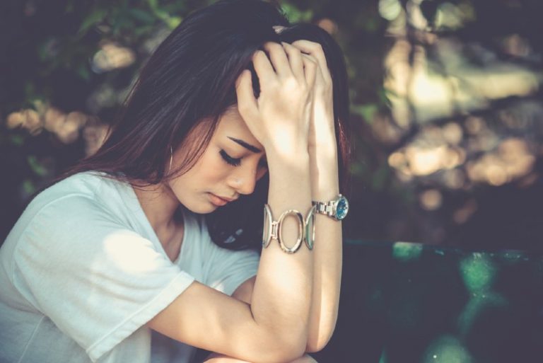 Profil de assis triste belle femme avec sa tête dans ses mains