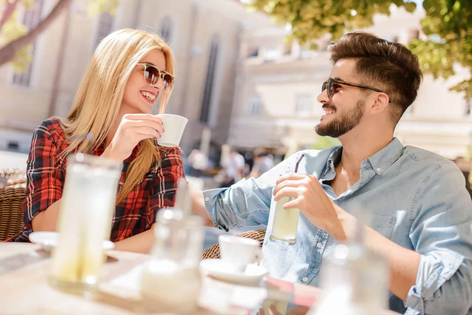 un couple amoureux assis à l'extérieur et buvant du café