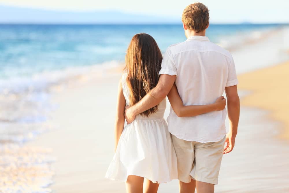 un homme et une femme marchent le long de la plage