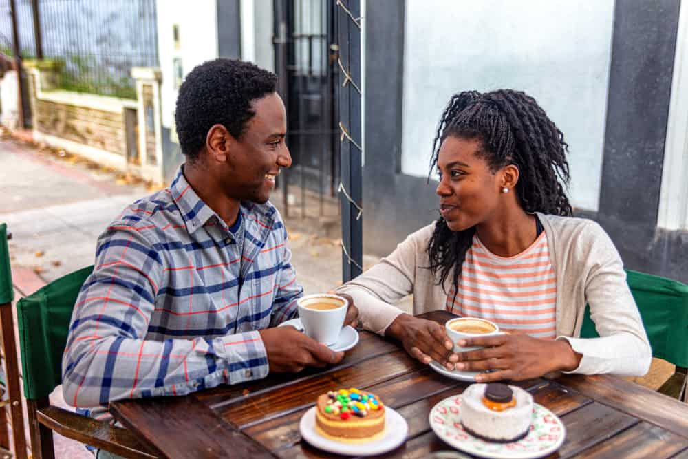 un homme et une femme s'assoient à une table et boivent du café