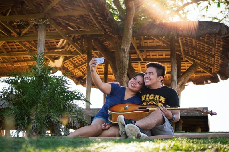 un homme et une femme s'assoient avec une guitare et prennent des photos