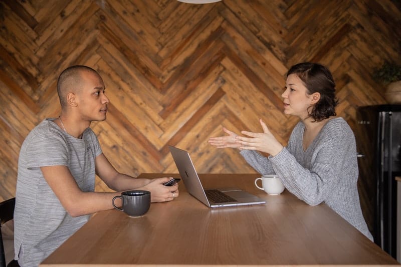 un homme et une femme sont assis à une table face à face et parlent