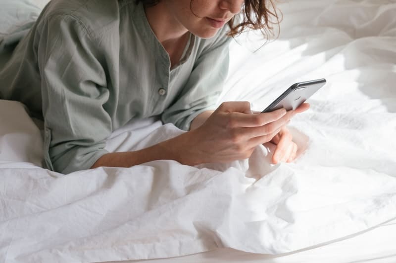 une femme au lit avec un téléphone à la main