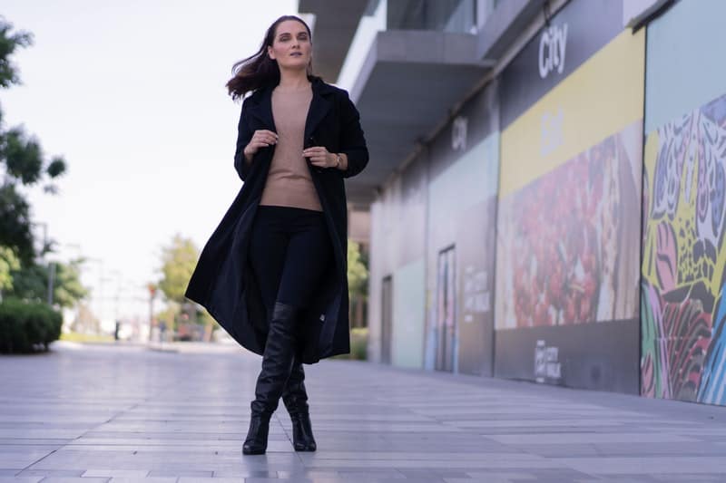 une femme avec un manteau noir marche dans la rue