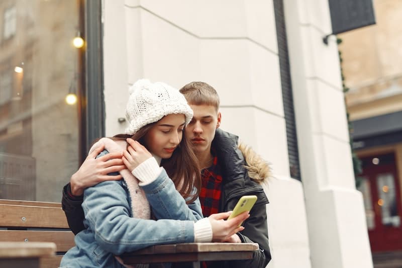 une femme boutons sur le téléphone pendant qu'un homme la serre dans ses bras
