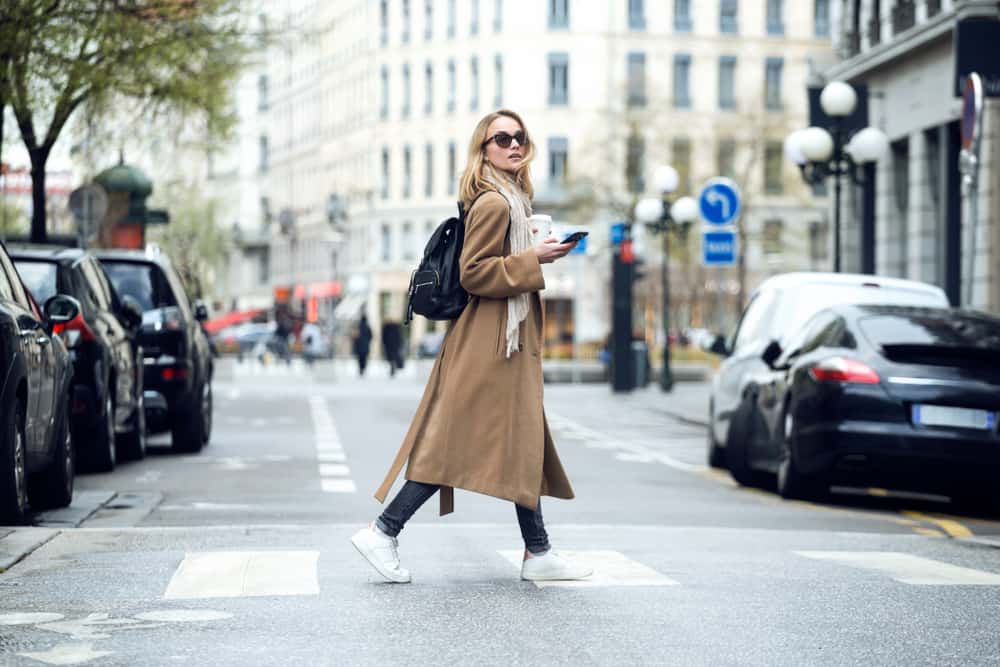 une femme en manteau marche dans la rue