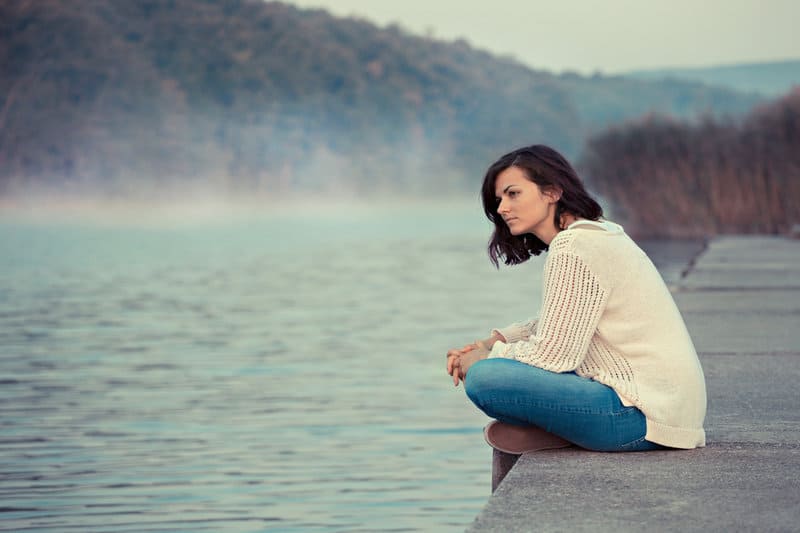 une femme imaginaire assise sur une jetée au bord de la rivière