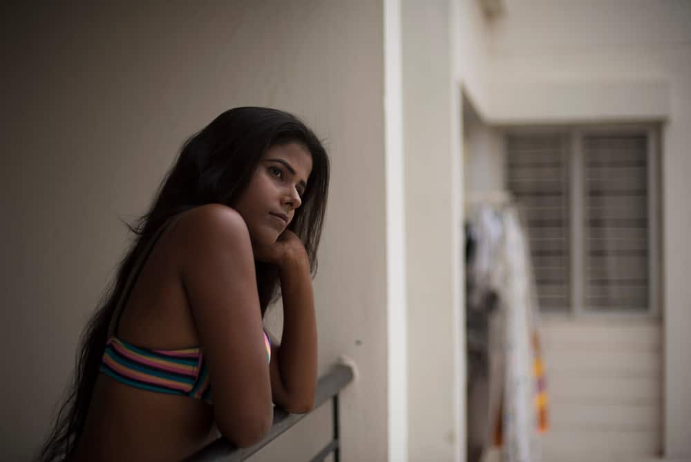 une femme imaginaire en maillot de bain se tient près de la clôture