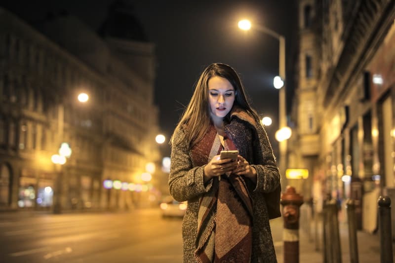 une femme marche dans la rue avec un téléphone à la main