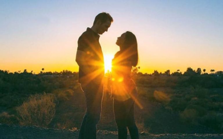 un homme et une femme sembrassent assis a cote de la jetee