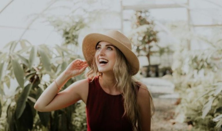 une femme aux cheveux blonds avec un chapeau sur la tete rit