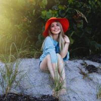 une femme aux cheveux blonds avec un chapeau rit