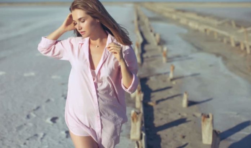 une femme en chemise rose marche sur la plage