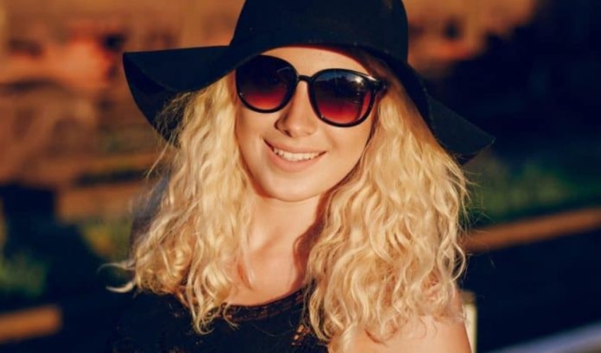 une femme blonde avec un chapeau noir