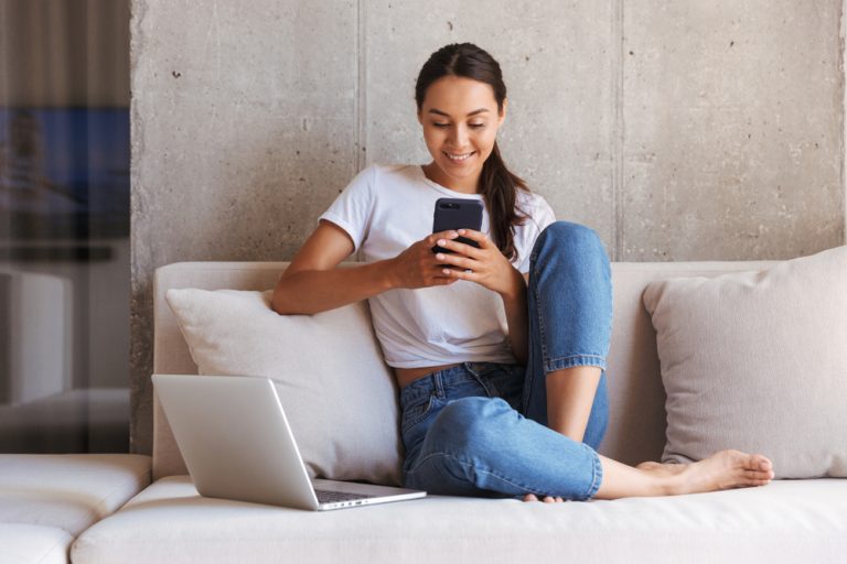 la femme s'assied sur le canapé et écrit un message