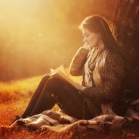 la fille est assise sous un arbre et lit un livre