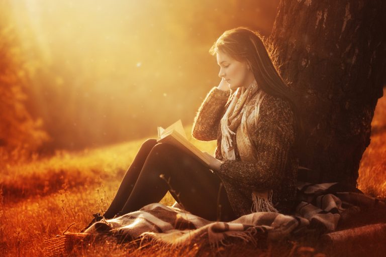 la fille est assise sous un arbre et lit un livre