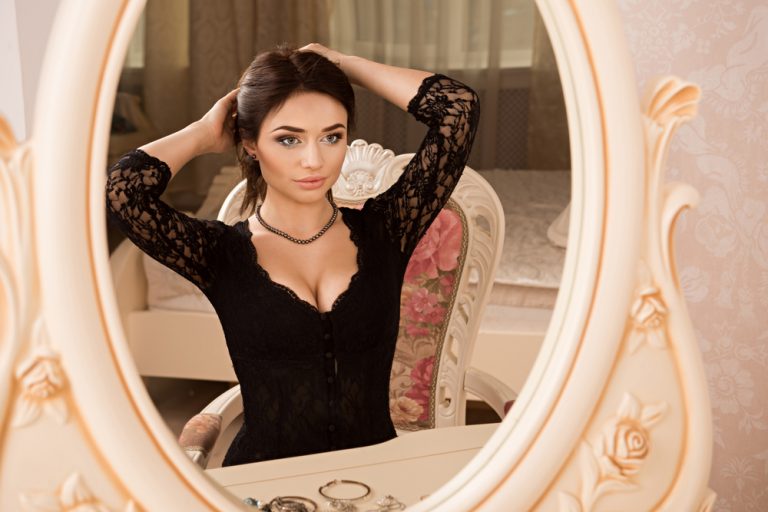 une femme dans une robe moulante noire regarde dans le miroir