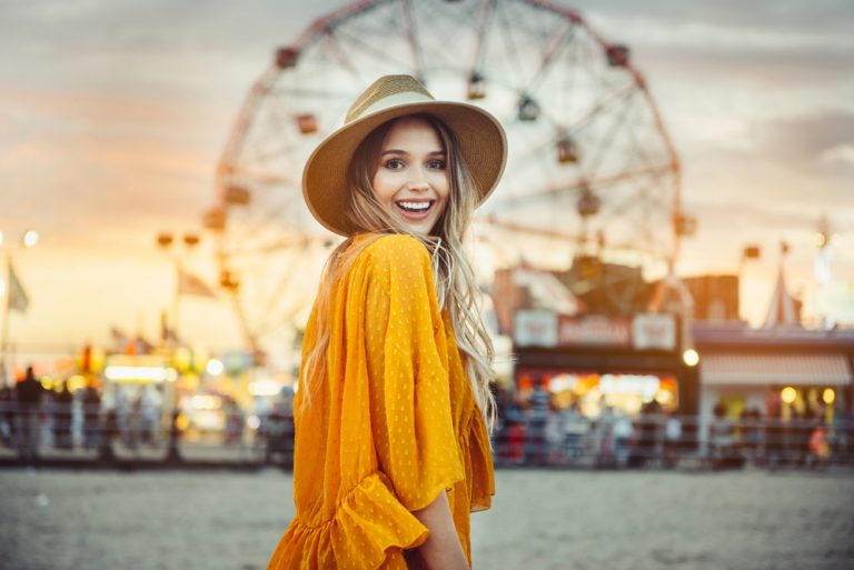 une femme avec un chapeau se tient dans un parc