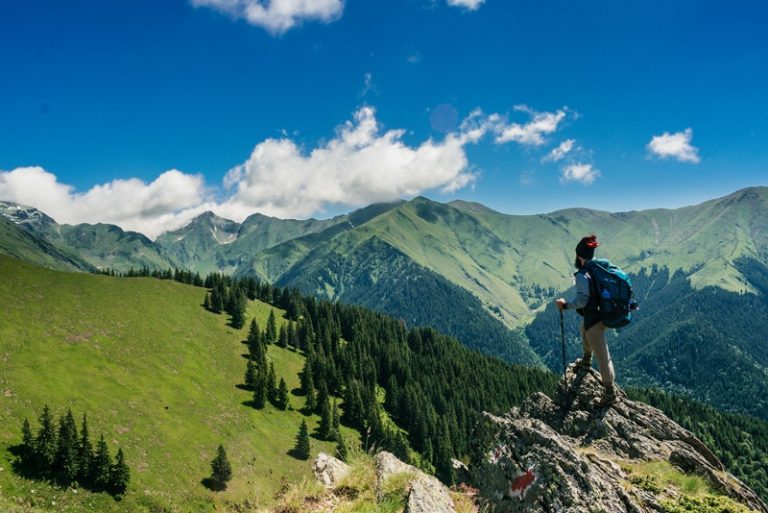 l'alpiniste se tient sur un rocher et regarde la montagne devant lui