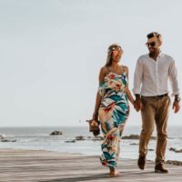 un homme et une femme marchant sur la plage main dans la main